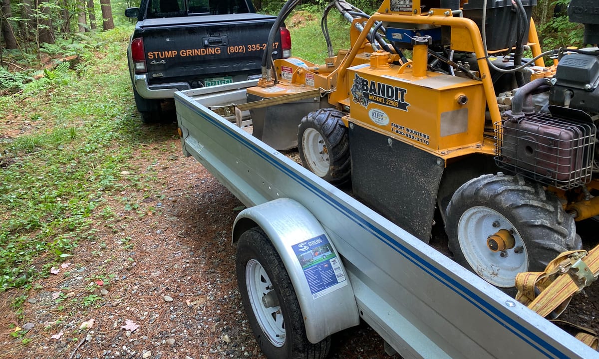 Grinding Gears stump grinder loaded on a trailer behind the company pickup at a Vermont job site