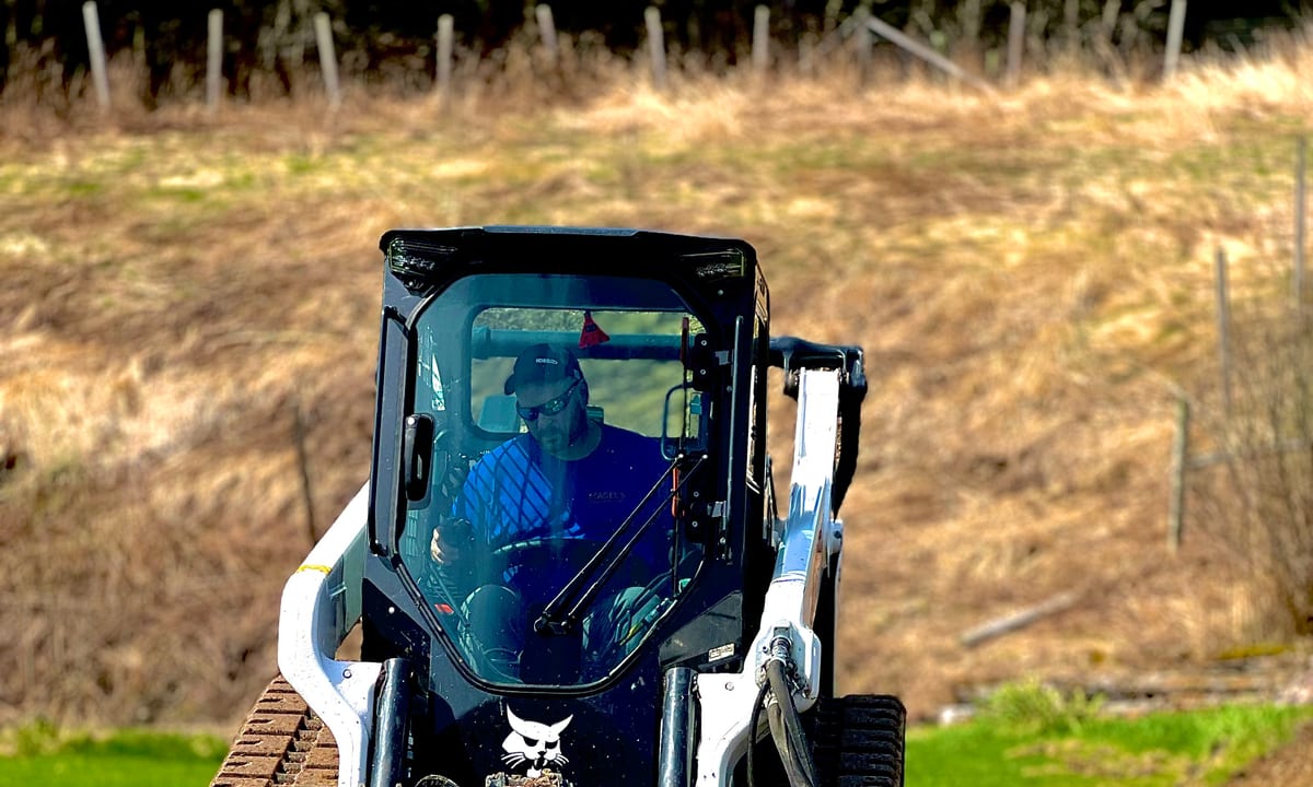 Magee's Excavation skid steer grading soil on a Vermont site